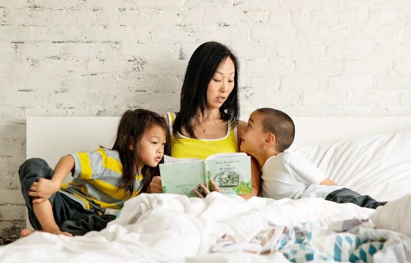 Một bà mẹ đang tập thể dục nhẹ nhàng cùng em bé hoặc khuyến khích bé vận động để cải thiện táo bón
