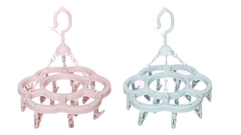 Một bà mẹ trẻ đang phơi quần áo em bé trên giá treo quần áo inox gấp gọn, thể hiện sự tiện lợi và gọn gàng.